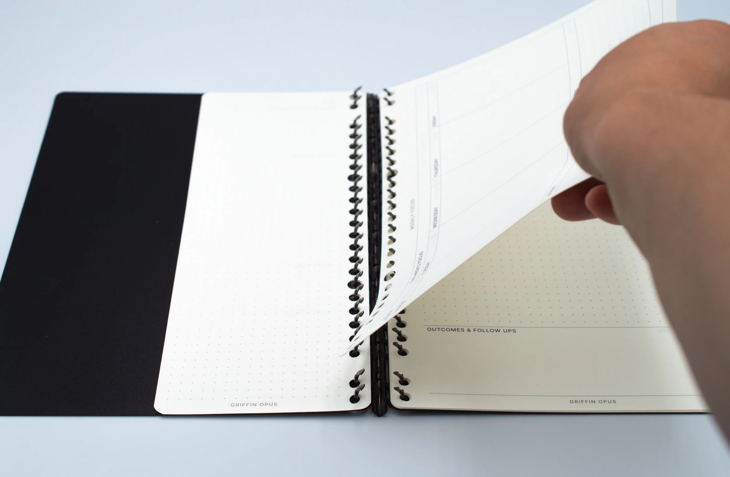 An open B5 binder with a handwritten day plan laid out in time slots on a wooden desk